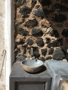 um lavatório de pedra sentado em cima de uma parede de pedra em Dammusi IL SERRALH -Pantelleria- em Pantelleria