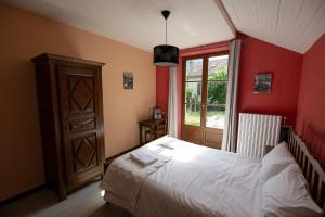 1 dormitorio con cama blanca y ventana en Le Roucadel, en Peyreleau