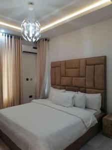 a bedroom with a large white bed and a chandelier at Lovely 2 bedroom in ikate in Lekki