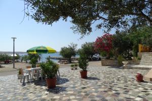 un patio con mesa, sombrilla y plantas en Apartments Vivien en Kustići