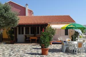a house with a table and chairs and an umbrella at Apartments Vivien in Kustići