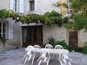 une table et des chaises blanches devant un bâtiment dans l'établissement Le Clos du Merry, à Joux-la-Ville