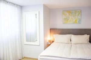a white bedroom with a bed and a window at Stacey’s Stylish studio in Eilat