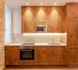 a kitchen with wooden cabinets and a sink and a microwave at San Bernardino 15 in Madrid