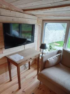 a living room with a couch and a table and a tv at Le P'tit Nid : Mini loft pour 2 à 4 personnes in Tellin