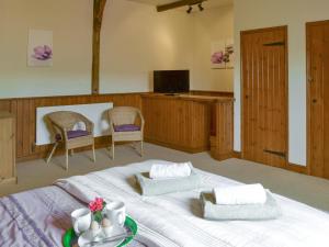 a bedroom with a large bed with two chairs and a television at The Old Stables in Freethorpe
