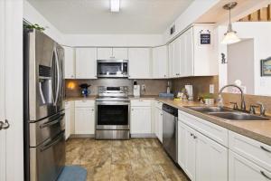 a kitchen with white cabinets and a stainless steel refrigerator at Pelican Path in Galveston