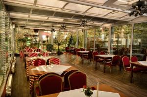 a restaurant with tables and red chairs and windows at Hotel am Stadtwald in Stralsund