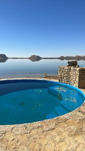 Siwa Relax Retreat Ecolodge في سيوة: مسبح ازرق كبير بجانب جسم ماء