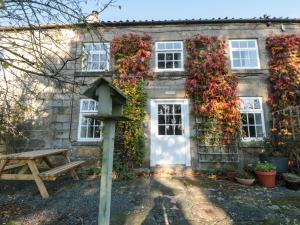 a house covered in ivy with a white door at The Cottage in Pickering