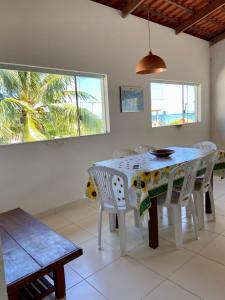 uma sala de jantar com uma mesa e cadeiras brancas em apartamento de frente para o mar em Vera Cruz de Itaparica