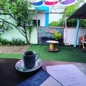 a cup of coffee sitting on a table in a backyard at Pousada Caragua Poesia na Praia in Caraguatatuba