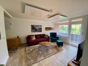 a living room with a red couch and blue chairs at Appartement Vogelkoje Nummer 35 in Baiersbronn
