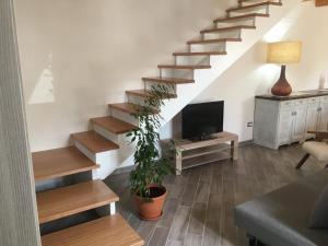 a living room with a staircase with a tv at Domu Quesada in San Giovanni Suèrgiu