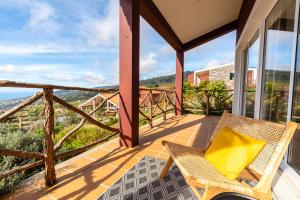 a balcony with a chair and a view of the ocean at Yeotown Health Retreat in Arco da Calheta