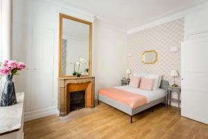 Schlafzimmer mit einem Bett, einem Kamin und einem Spiegel in der Unterkunft Cosy 3 bedroom and 2 Bathroom - Opera in Paris