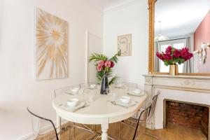 ein weißes Esszimmer mit einem weißen Tisch und einem Kamin in der Unterkunft Cosy 3 bedroom and 2 Bathroom - Opera in Paris