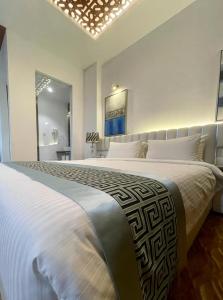 a white bedroom with a large bed with white pillows at Empyrean Dhaka City Centre in Dhaka