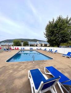 uma piscina com cadeiras azuis e brancas num quintal em Loft LèSKImo, lit king, sauna, piscine et montagne em Saint-Férréol-les-Neiges
