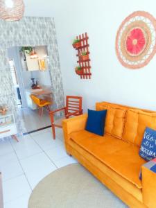 a living room with an orange couch and a dining room at Casa Arembepe in Camaçari