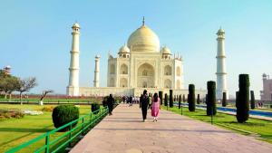 un grupo de personas caminando delante del taj mahal en Superinn home stay& guest house, en Agra