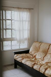 1 cama no hecha en un dormitorio con ventana en Leguizamon Flat - MZA Travel en Godoy Cruz