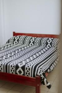Una cama con una manta blanca y negra. en Leguizamon Flat - MZA Travel en Godoy Cruz