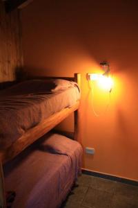 1 dormitorio con 1 cama y una luz en la pared en La Colorida en Lago Puelo