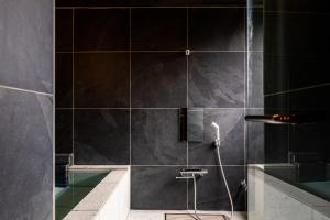 uma casa de banho com um chuveiro com azulejos pretos em Yoshino em Ito