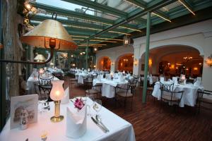 a restaurant with white tables and chairs and a lamp at 4-Sterne Superior Erlebnishotel Colosseo, Europa-Park Erlebnis-Resort in Rust