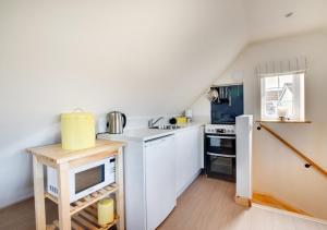 a small kitchen with white cabinets and a refrigerator at Swift Lodge in Kirton