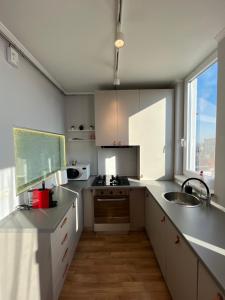 a kitchen with white cabinets and a sink and a window at Urbanna Premium - private parking included in Arad