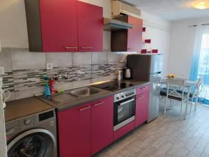 a kitchen with red cabinets and a washing machine at Apartments Katarina in Vis