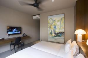 a bedroom with a white bed and a tv at Silalima in Kuantan