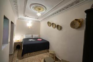 Riad Fez Unique في فاس: غرفة صغيرة بها سرير وقبعتين على الحائط