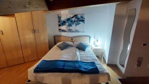 ein Schlafzimmer mit einem großen Bett mit blauen Kissen in der Unterkunft Loft della Perpetua di Casa Bernardi, romantica mansarda nelle Dolomiti di Brenta in Montagnaga