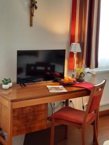 een bureau met een televisie en een rode stoel bij Gästehaus Klosterhof Schweiklberg in Vilshofen an der Donau