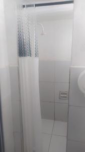 a shower with a shower curtain and a sink at Pousada Cisne Branco in Natal