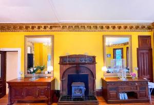 a living room with a fireplace and two mirrors at Catcune Grand Suite in Gorebridge