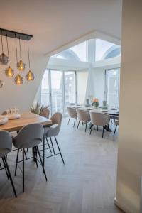 een eetkamer met een lange tafel en stoelen bij Penthouse Royal, Luxurious and cozy with Sauna in Cadzand