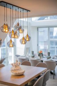 uma sala de jantar com mesa, cadeiras e luzes em Penthouse Royal, Luxurious and cozy with Sauna em Cadzand