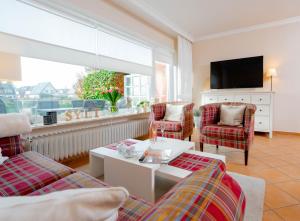 a living room with two couches and a tv at Haushälfte Stranddiestel in Wenningstedt