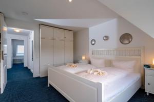 a bedroom with a white bed with two stuffed animals on it at Haushälfte Stranddiestel in Wenningstedt