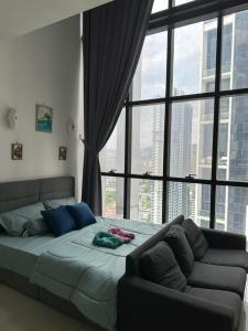 a bedroom with a bed and a couch in front of a window at EmEx Luxurious stay T2U29 in Kuala Lumpur