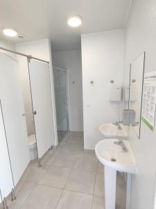 a white bathroom with two sinks and a shower at Camping Playa La Bota in Punta Umbría