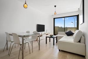 sala de estar blanca con mesa y sofá blanco en Gregal by enjoy Rocas Doradas en L'Ametlla de Mar