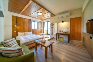 Habitación con cama, sofá y mesa. en Hejia B&B en Hualien