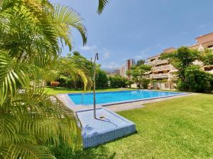 una piscina en un patio con una palmera en Pool Sunset Apartment, en Puerto de la Cruz