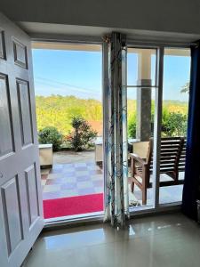 an open door to a patio with a view of the ocean at Hiddenvalley Stays - Nethra in Madikeri