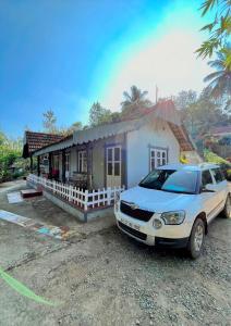 un coche aparcado frente a una casa pequeña en Hiddenvalley Stays - Nethra, en Madikeri